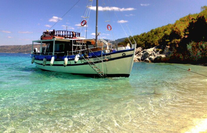 Tour boat anchored at the South Lagoon Sandbank in Corfu with crystal-clear shallow waters and passengers swimming during a half-day boat excursion.