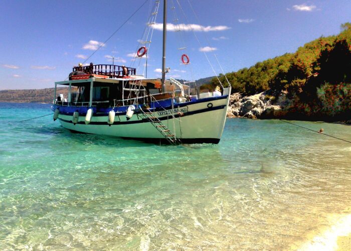 Tour boat anchored at the South Lagoon Sandbank in Corfu with crystal-clear shallow waters and passengers swimming during a half-day boat excursion.